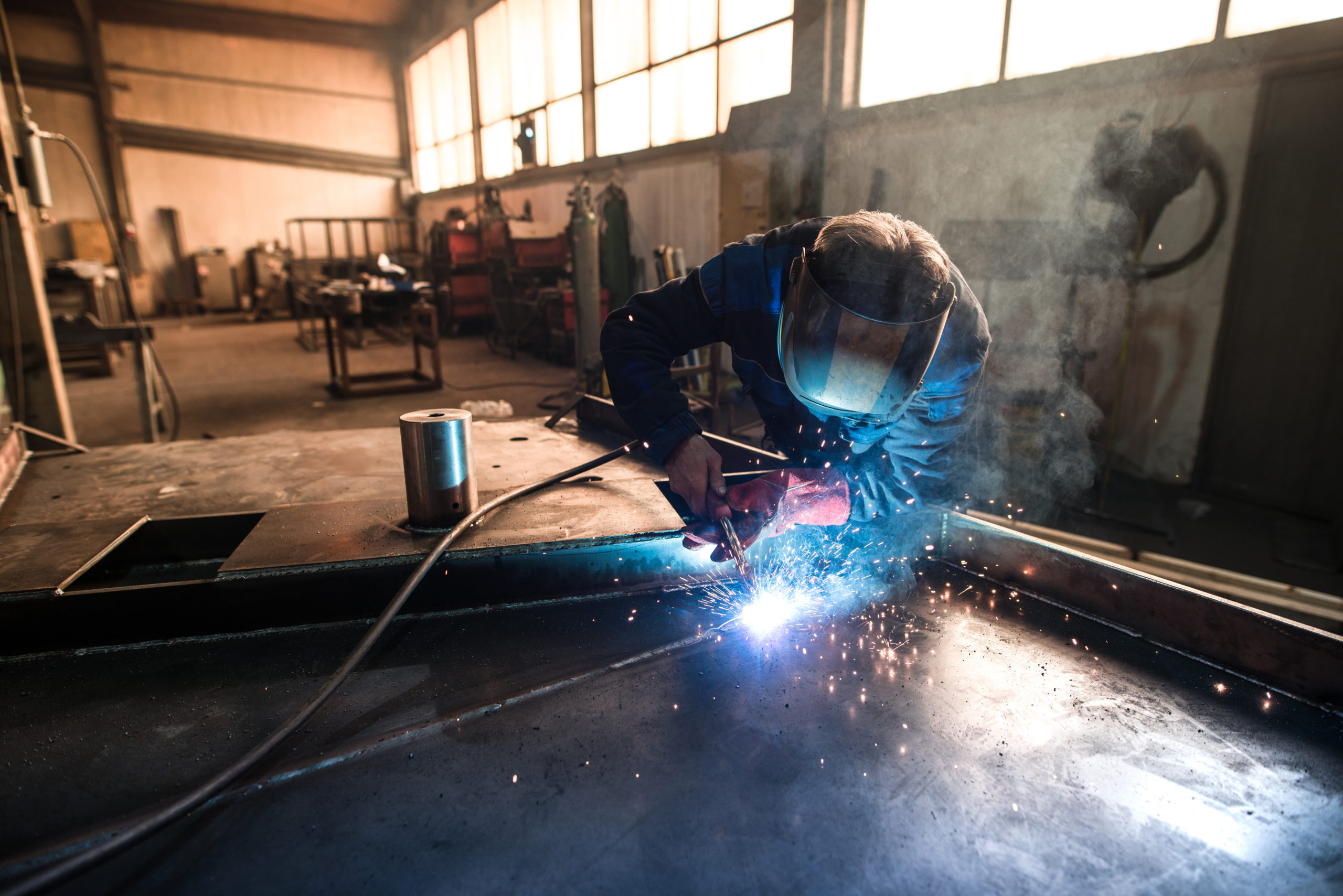 Man MIG Welding in Warehouse