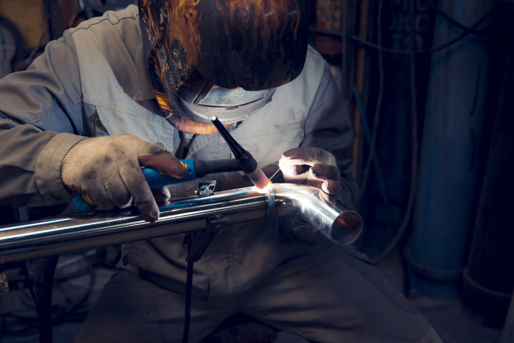 Man TIG welding a stainless steel pipe