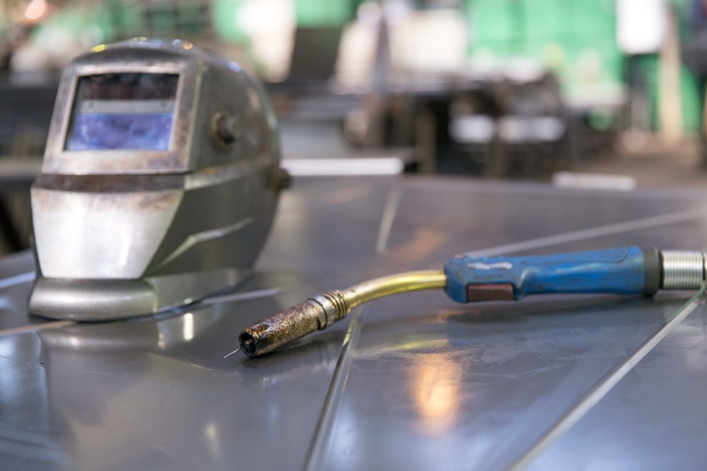 mig-gun-on-table-with-welding-helmet replacement of consumables
